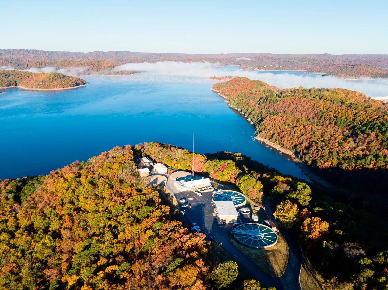 Aerial view of a lake surrounded by forest and autumn foliage