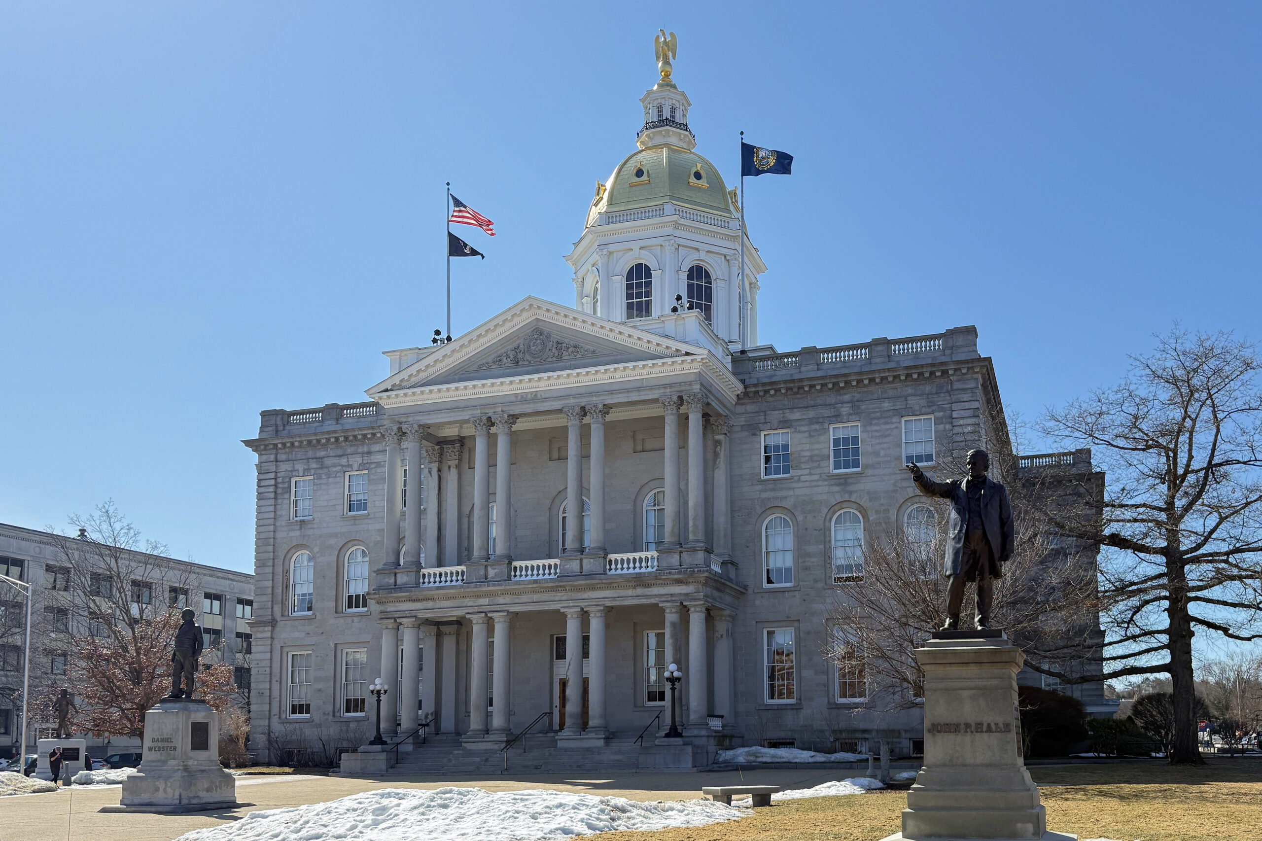 New Hampshire State House with flags and a statue in front