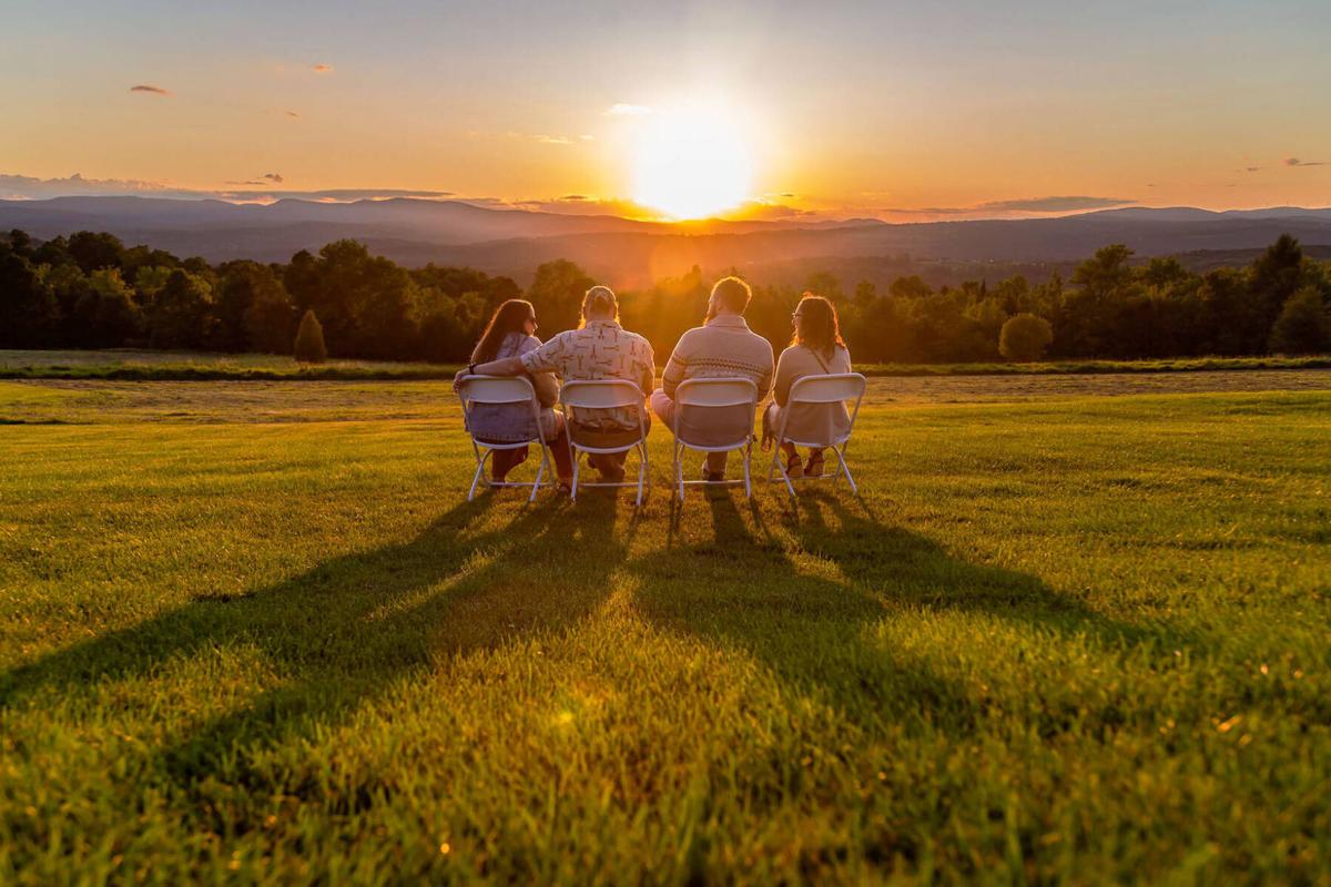 Group seated outdoors watching the sunset over rolling hills