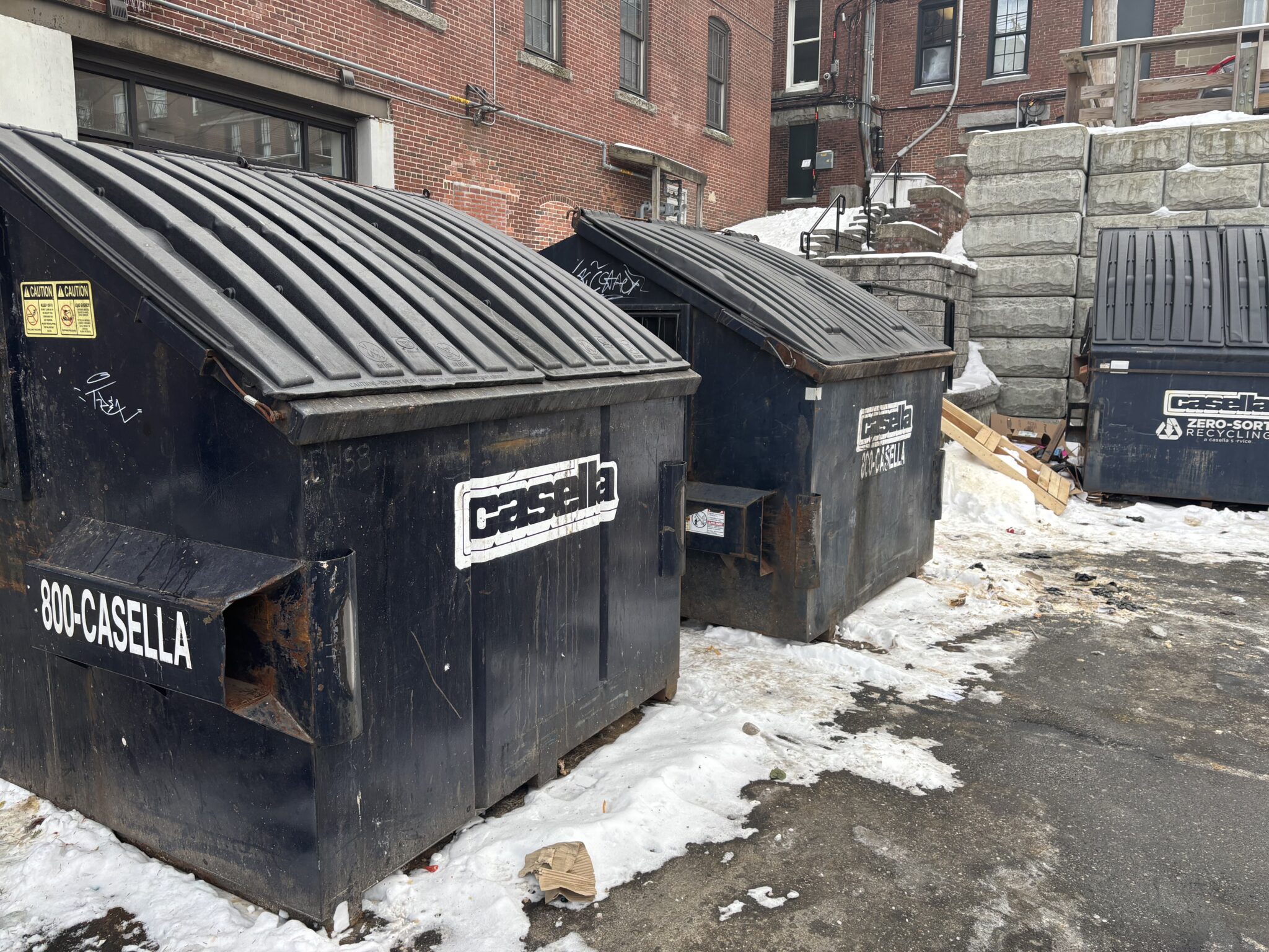 Casella dumpsters beside a brick building