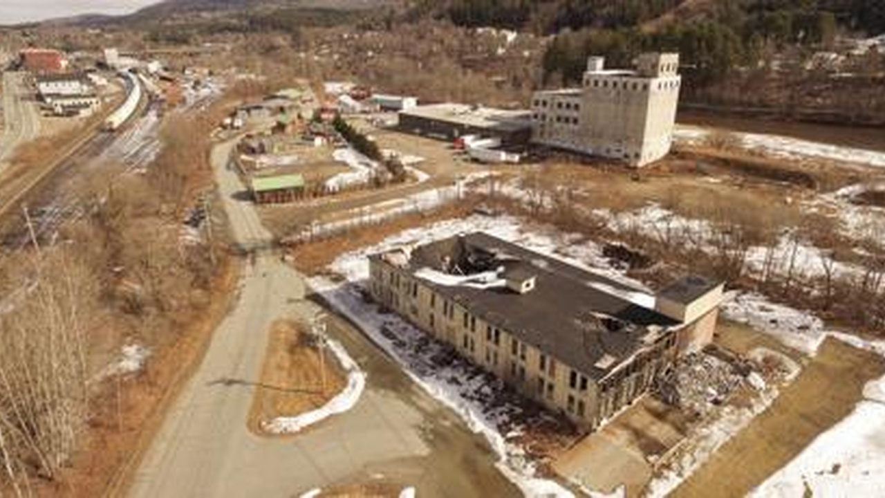 Aerial view of buildings and open land beside a road