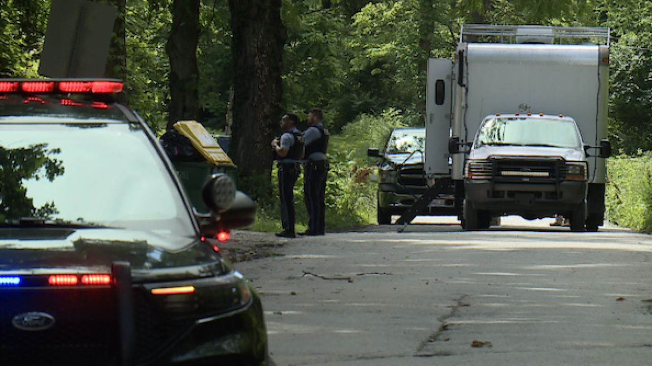 Police vehicles and officers on a road beside a parked box truck