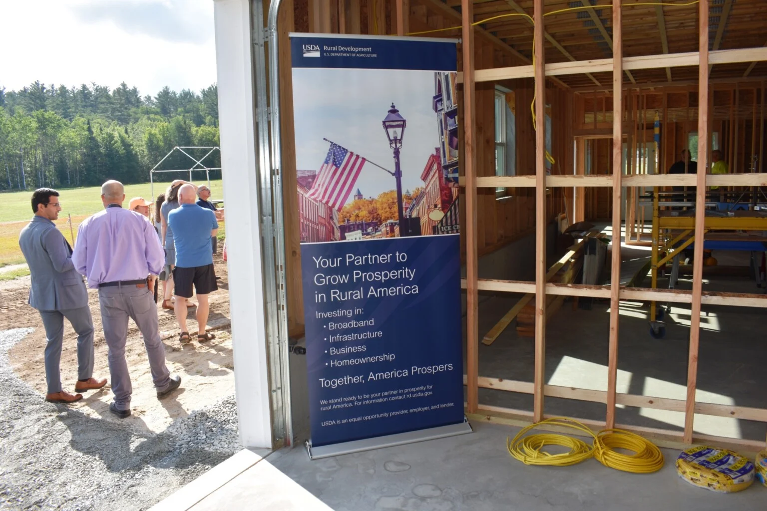Visitors beside a construction display at a partially framed building