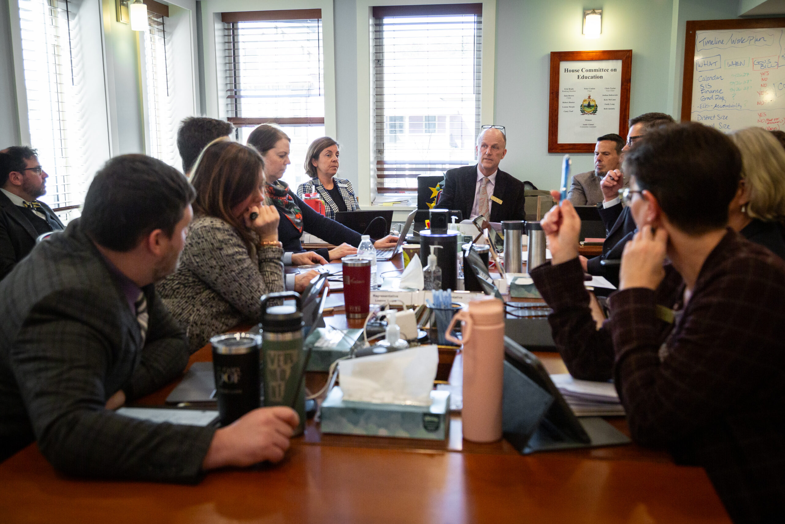Committee members seated around a meeting table in a hearing room